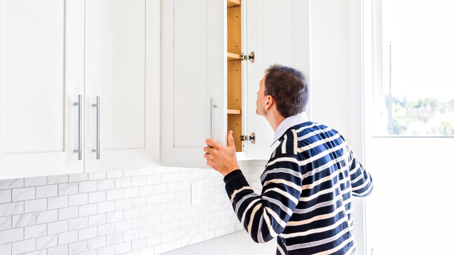 A man inspecting the kitchen cabinets for termites