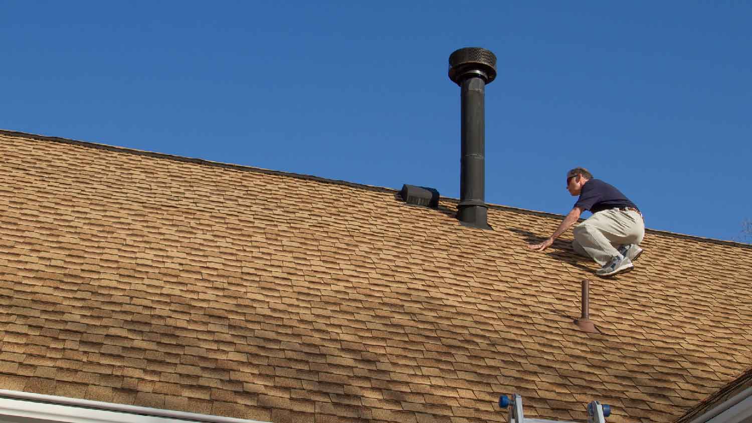 A man inspecting a roof vent