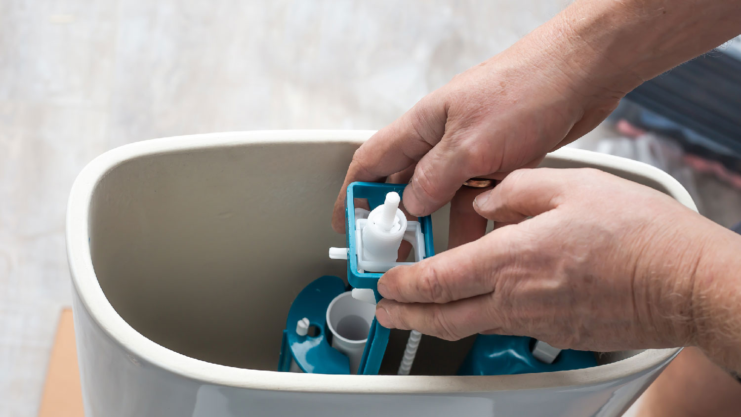 A man inspecting a toilet tank mechanism