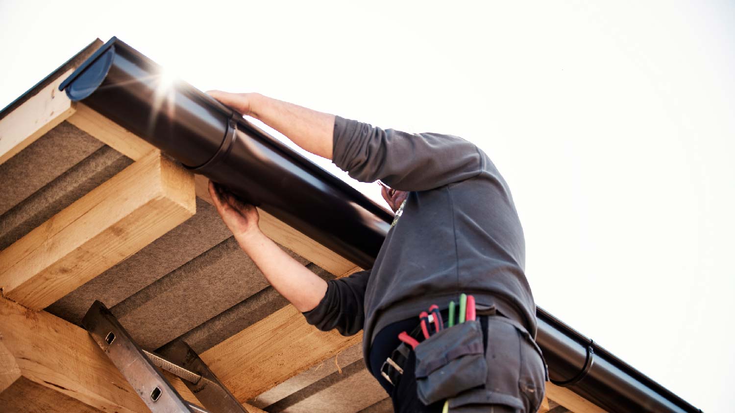 A man installing aluminum gutters