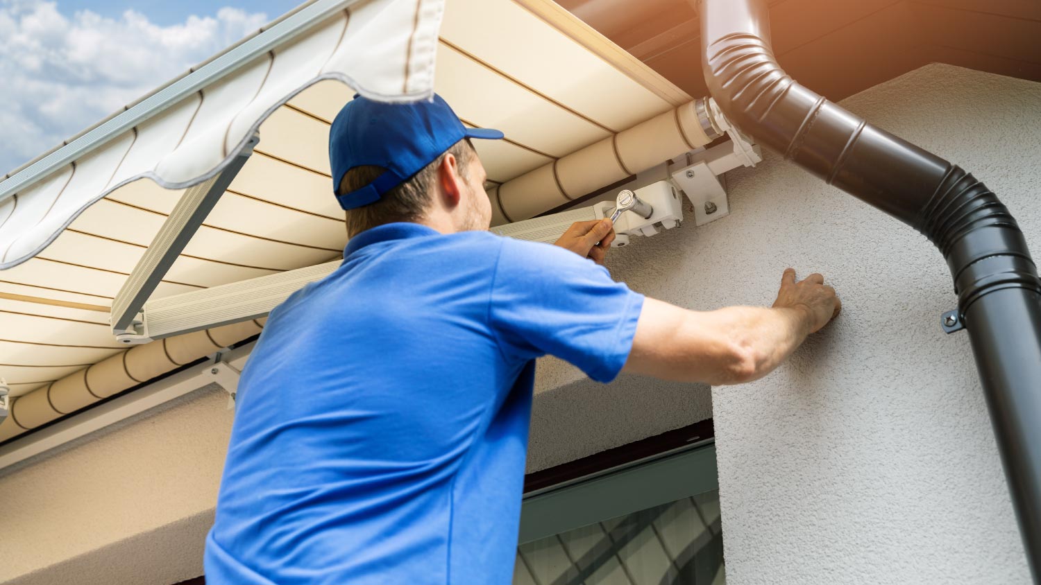 A man installing awning on house facade wall