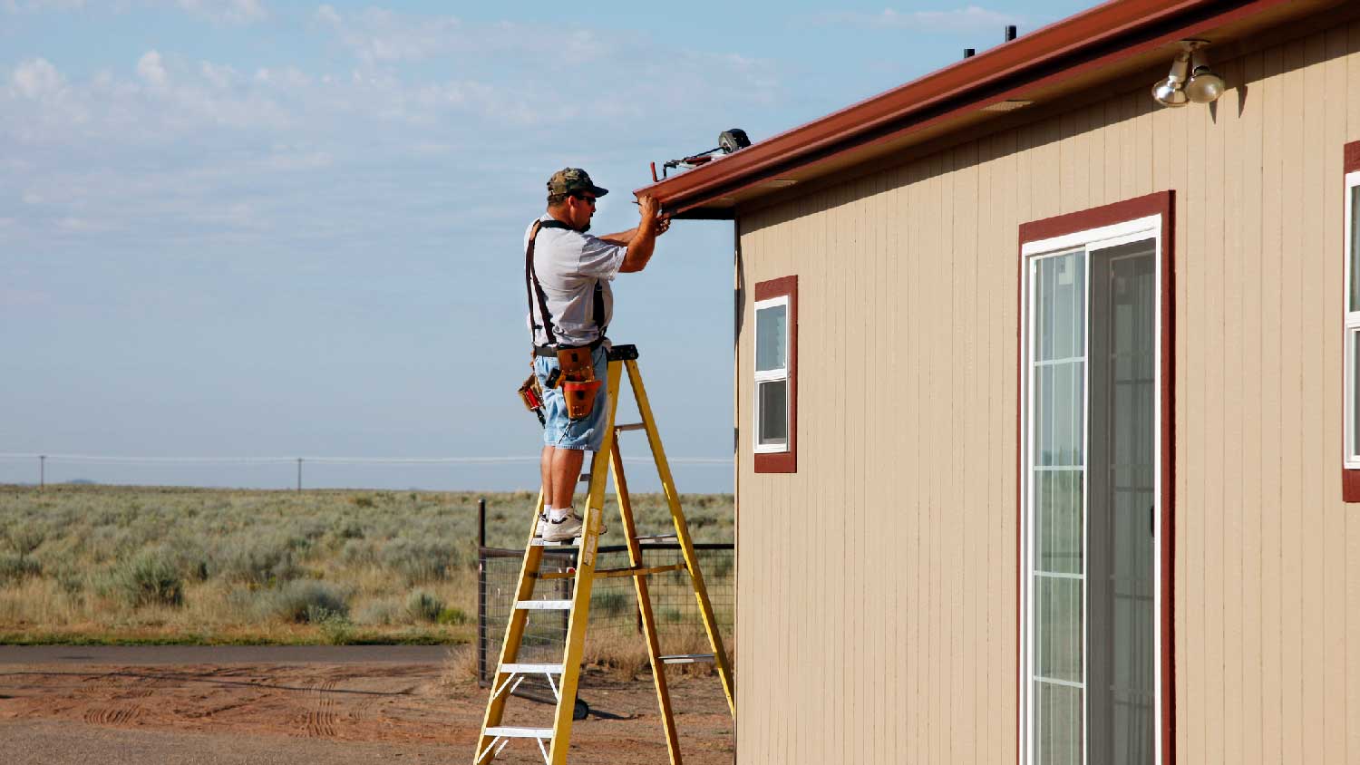 A man on a ladder installing downspout