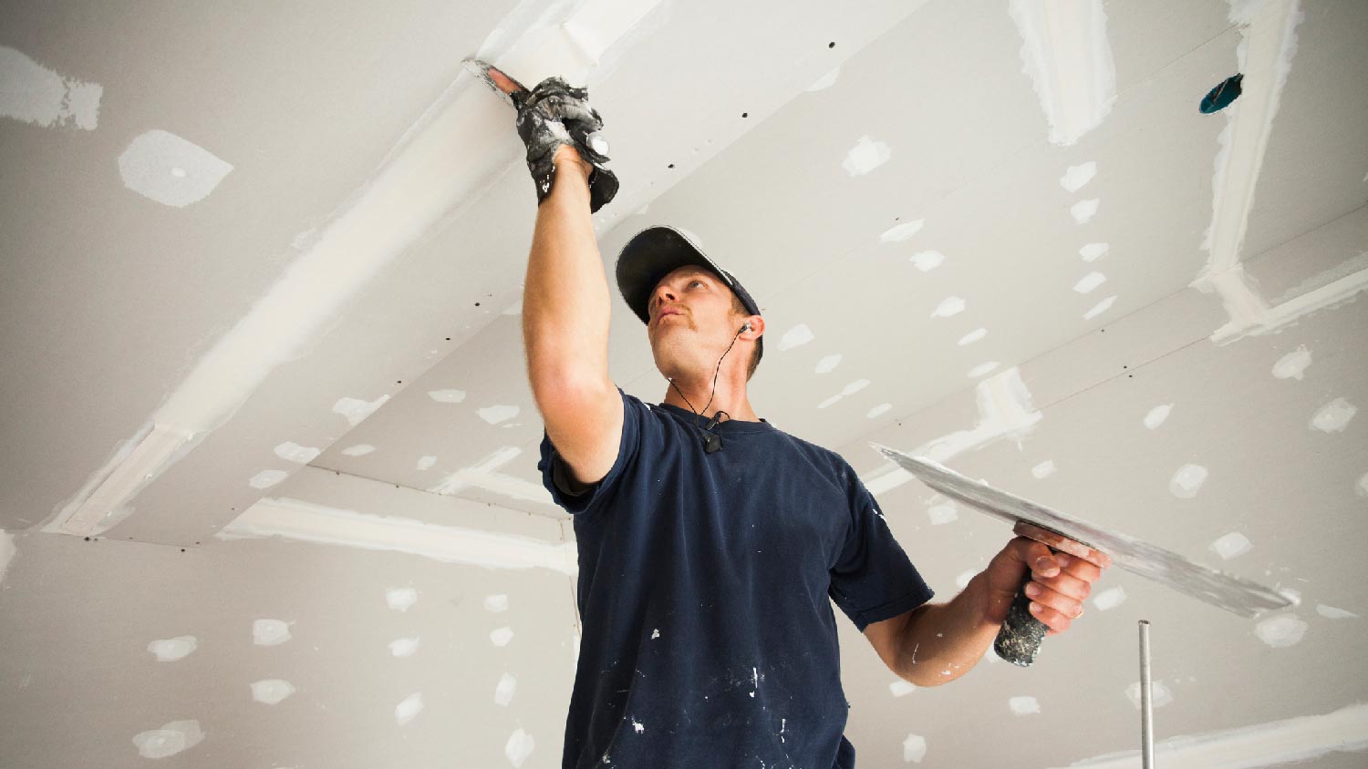 A man installing a drywall by taping and mudding