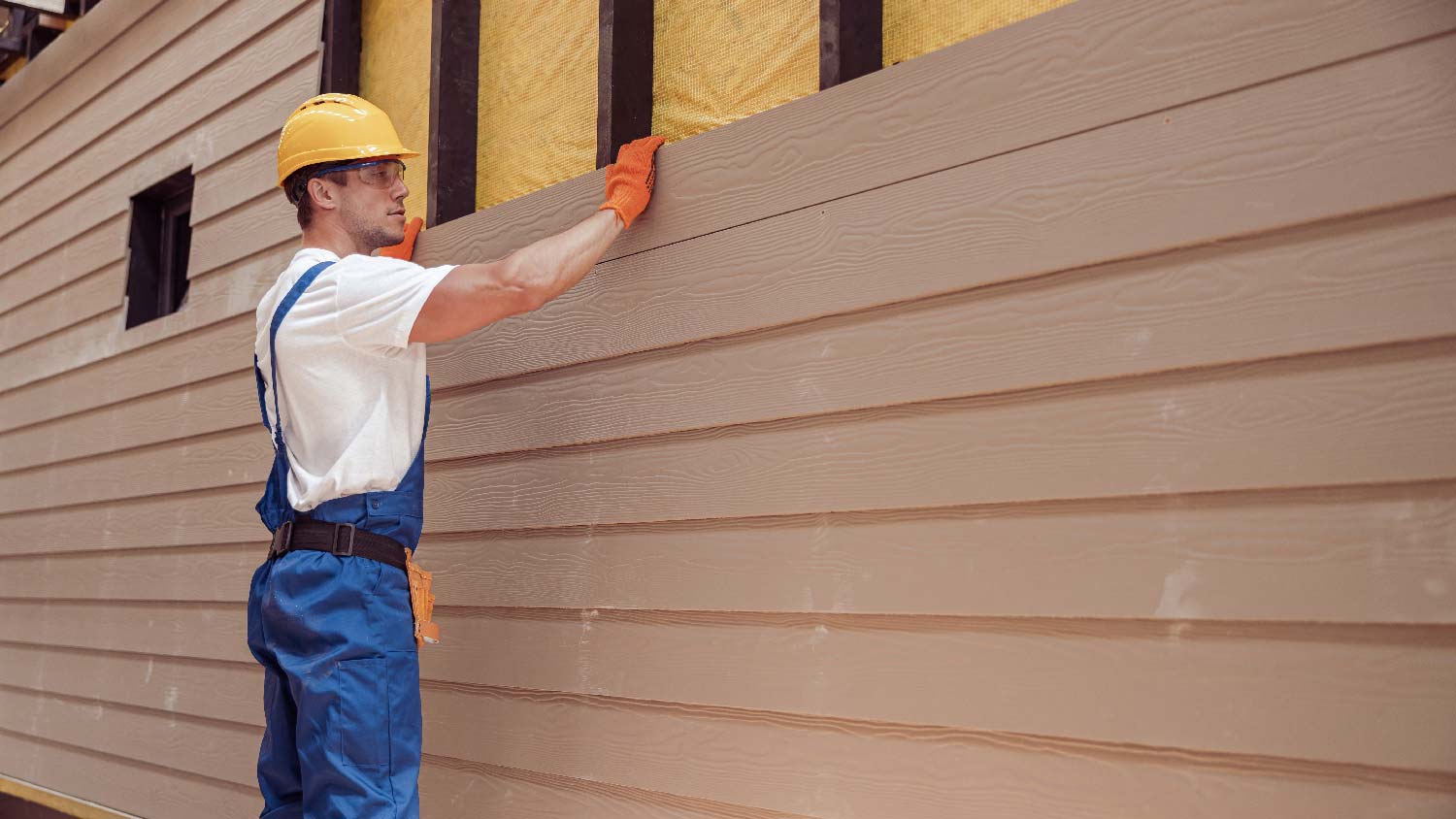 A man installing engineered wood siding