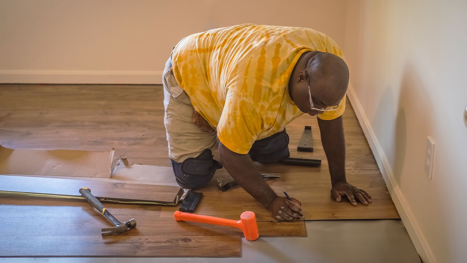 african american man installing new hardwood flooring