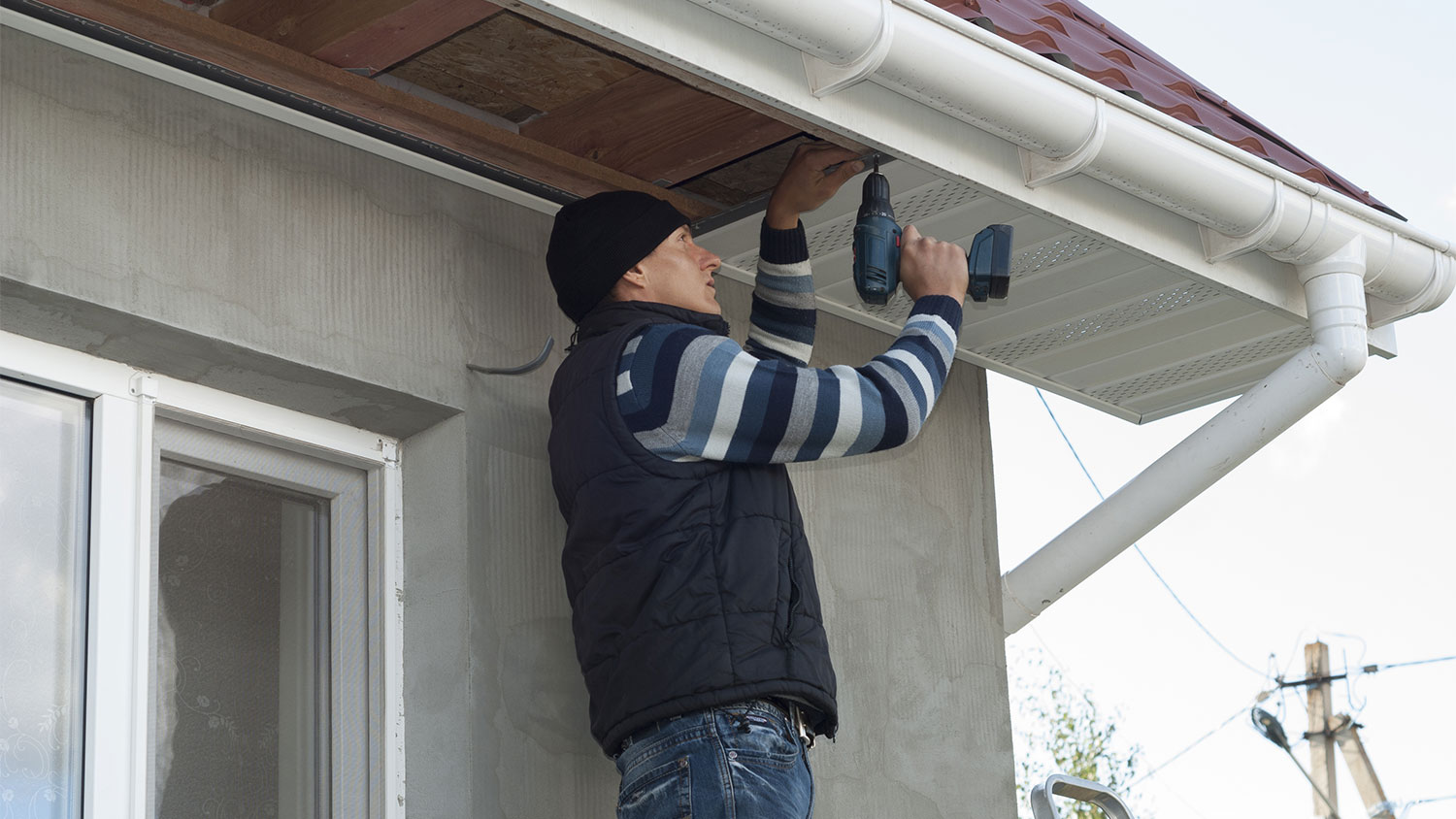 Man on a ladder installing new house soffit
