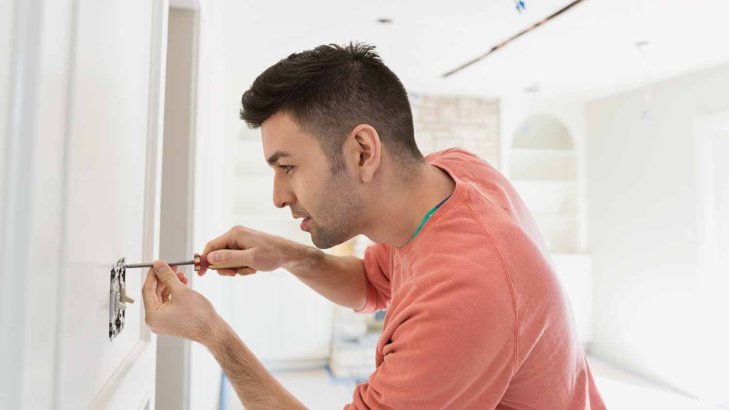 Man installing light switch at home