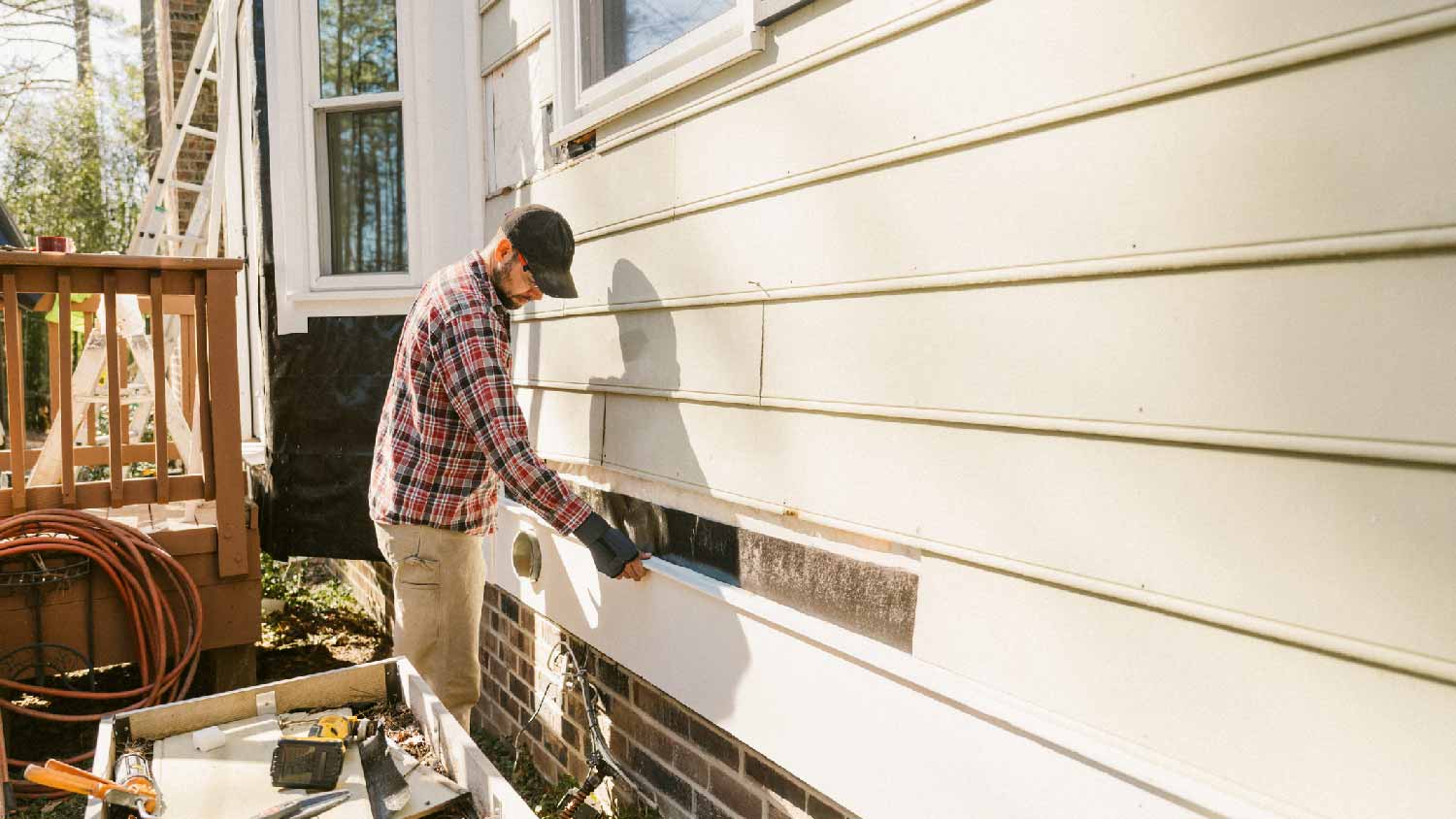 A man installing siding to a house
