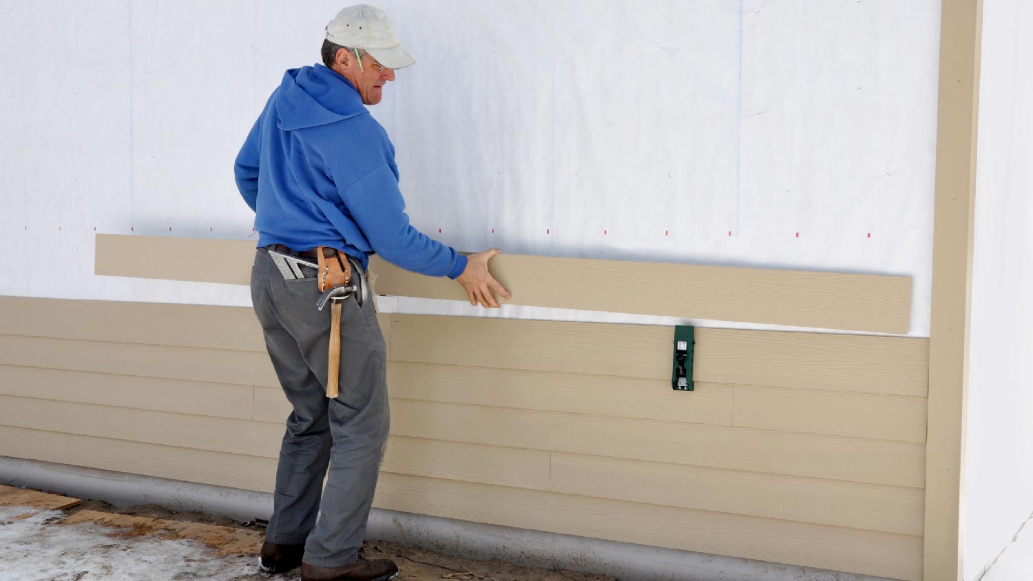 A man installing siding to a house