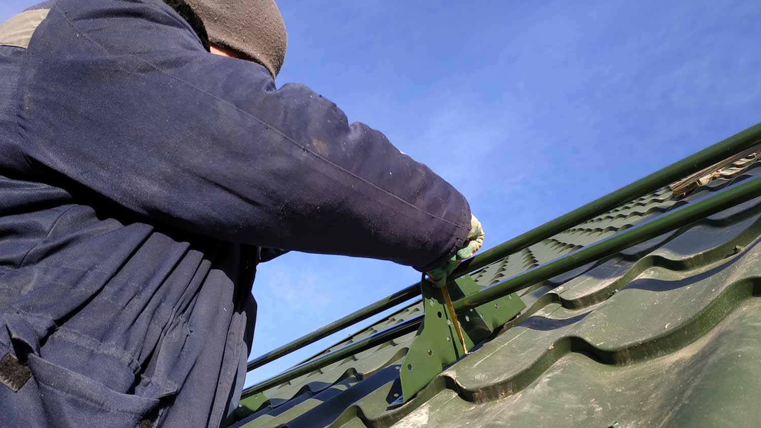 man installing snow guards on roof 