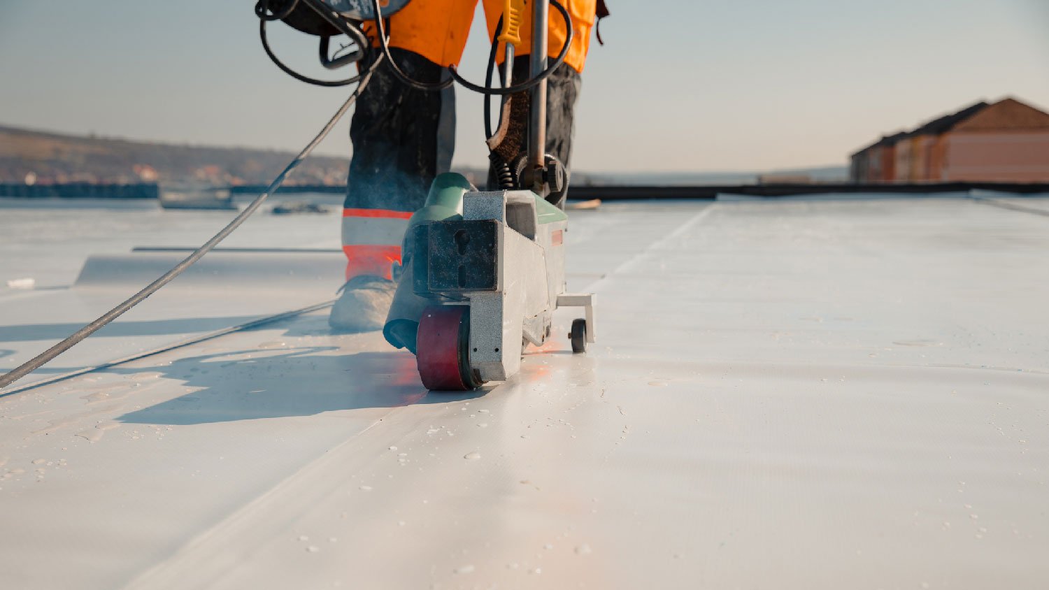 A man installing a vapor barrier on a flat roof