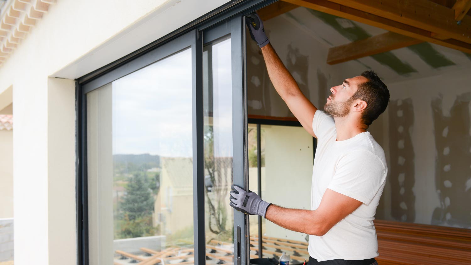 A man installing bay window in a new house construction