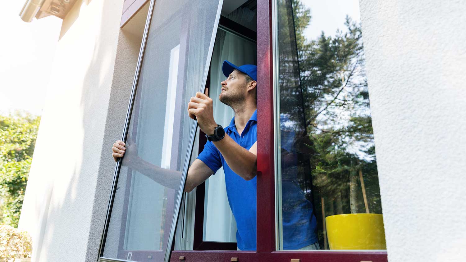 Worker in a house is installing new window screen