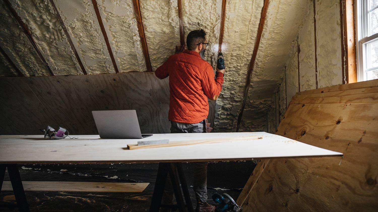 Man insulates attic with foam and puts plywood on top