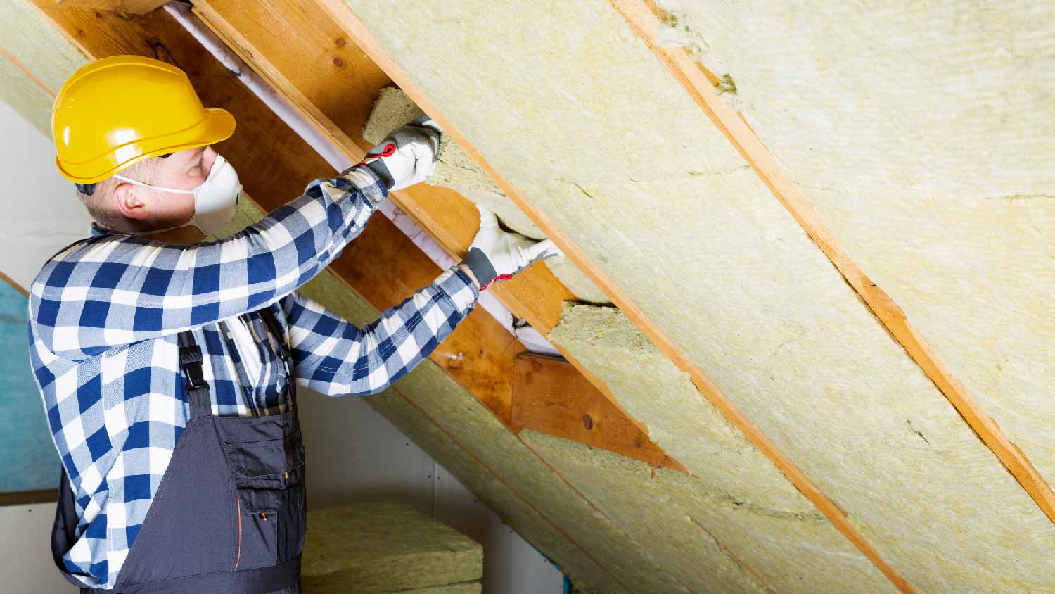 A man insulating an attic with batt and roll insulation