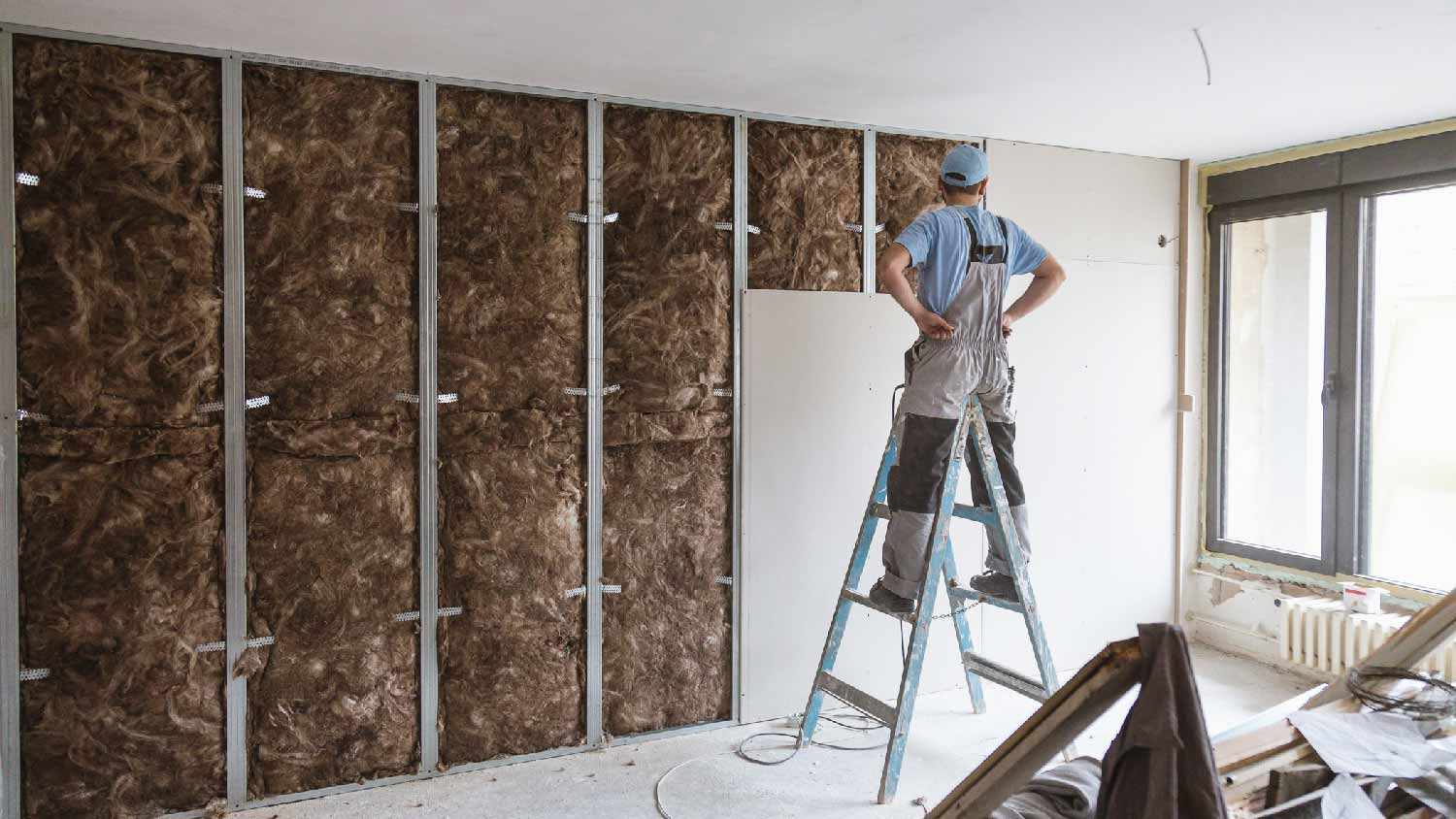 A man insulating a wall