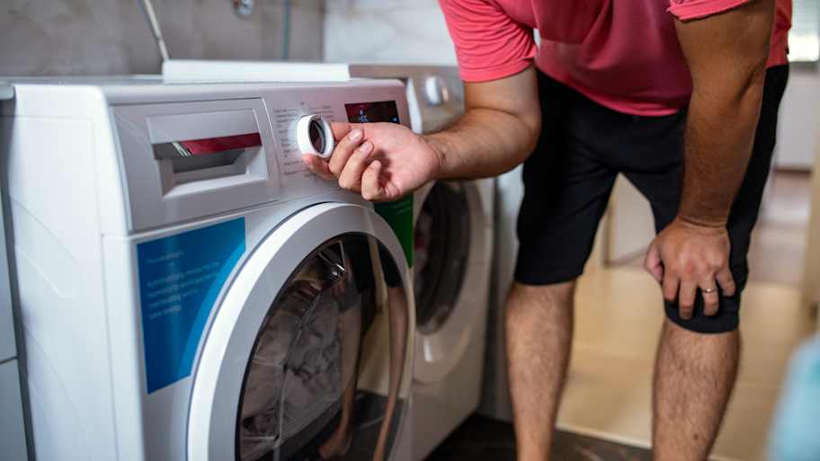 Man adjusting a washing machine in bathroom at home