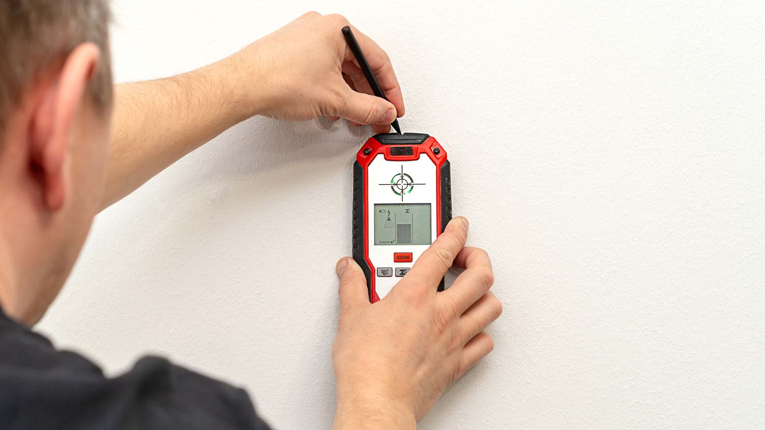 A man marking the wall by using a stud finder