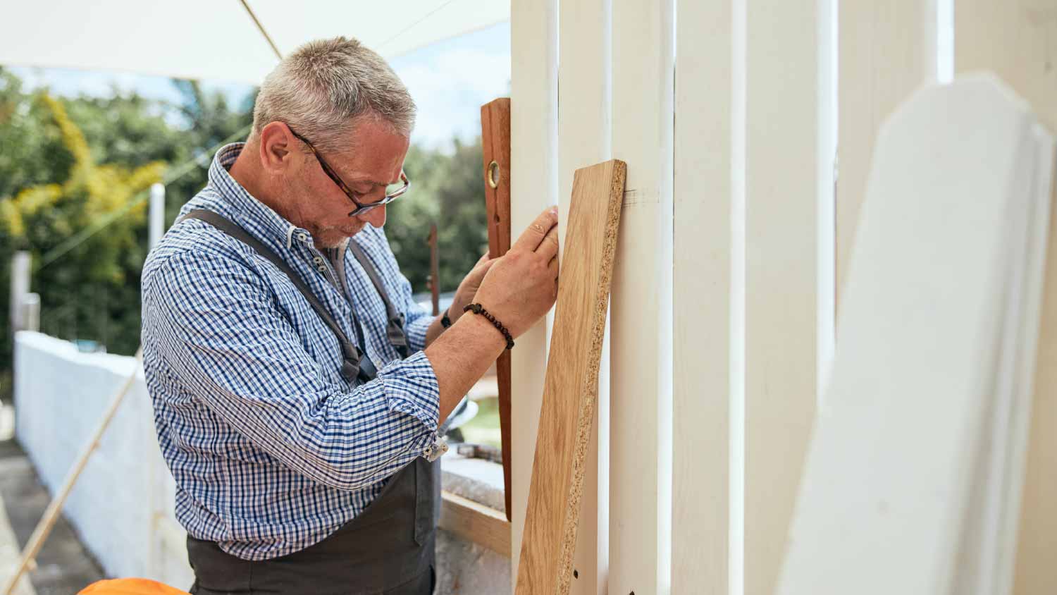 A man measuring a wooden plank