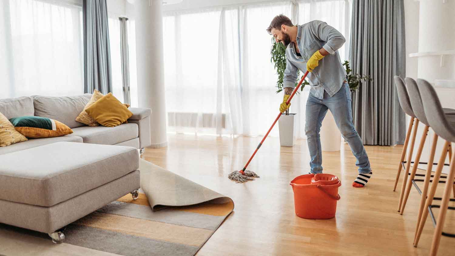 A man mopping the living room floor