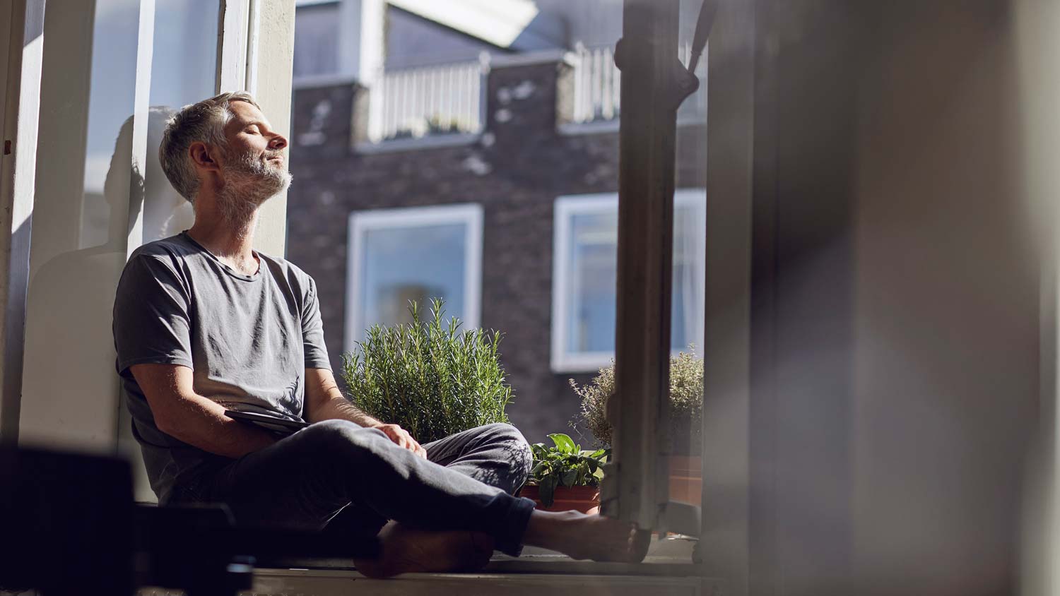 A man sitting by an open window enjoying the sun