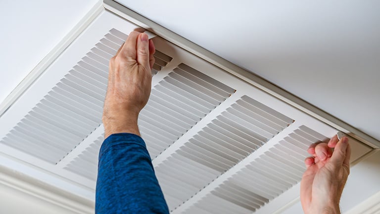 A man opening ceiling hvac to replace air filter