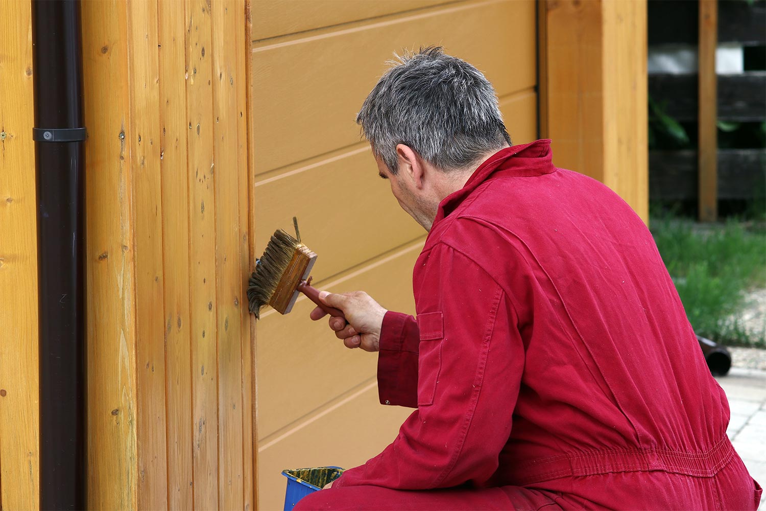 man using brush to paint garage door