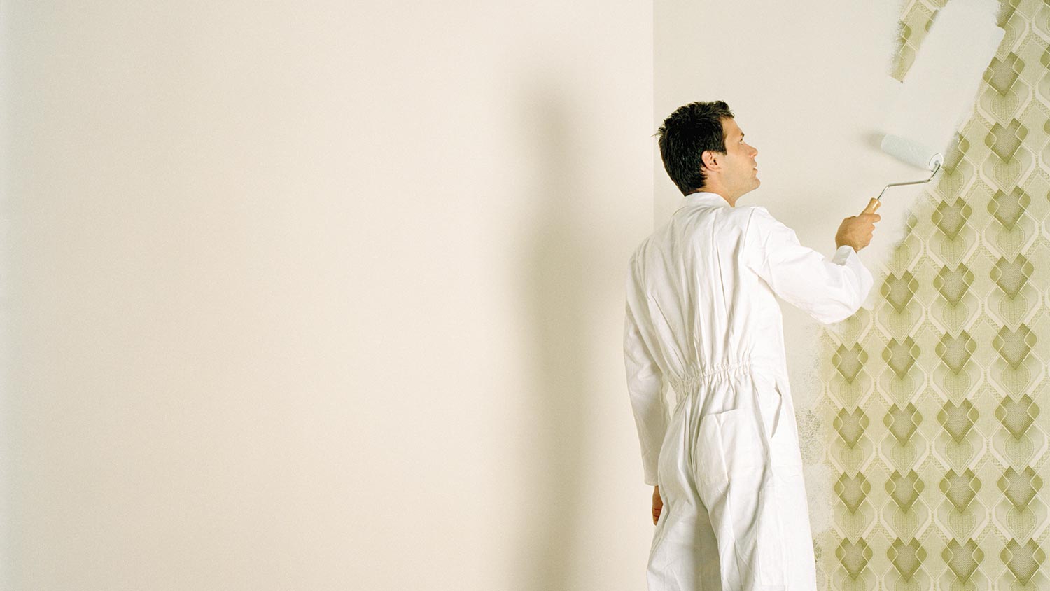 A man painting over a paintable patterned wallpaper 