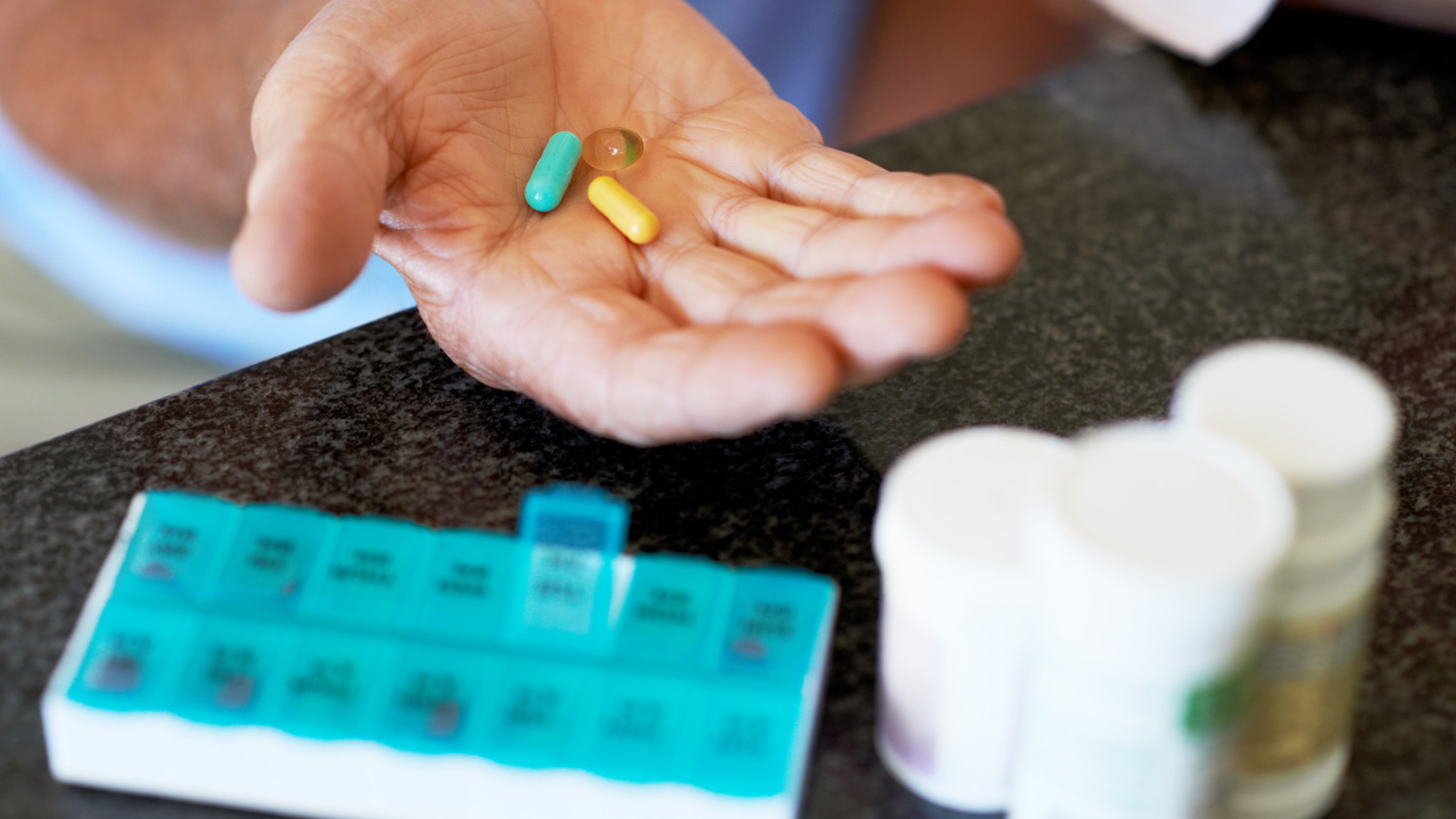 A senior man places his weekly pills in a medication dispenser