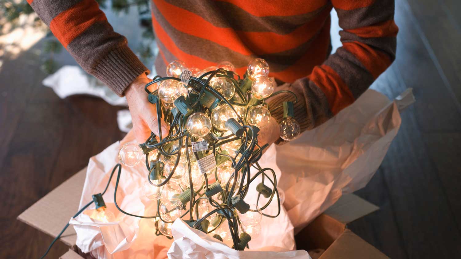 A man putting Christmas lights in a box