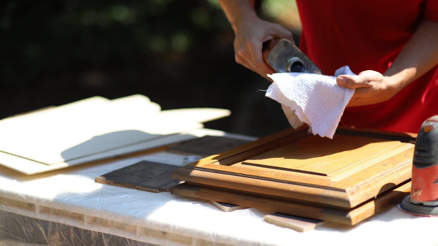 Close-up of man refinishing a kitchen cabinet door