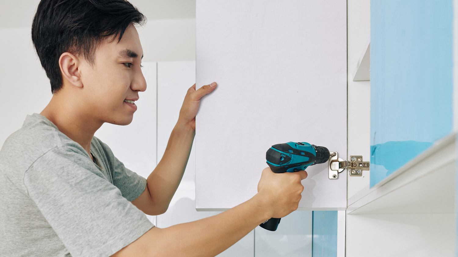 A man removing a kitchen cabinet door handle