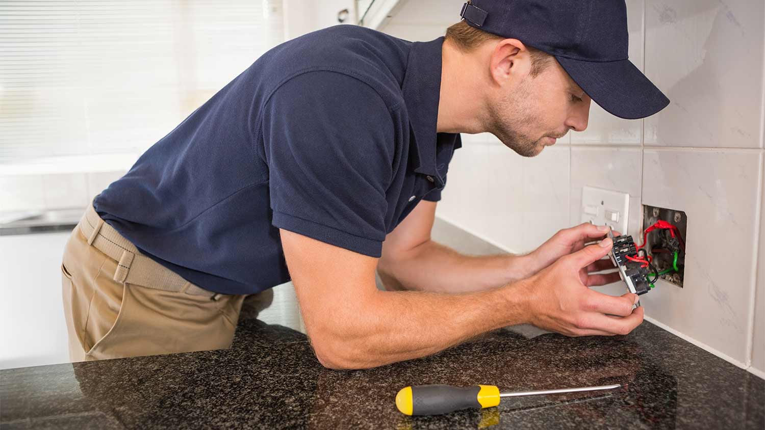 man checking wiring in kitchen power outlet