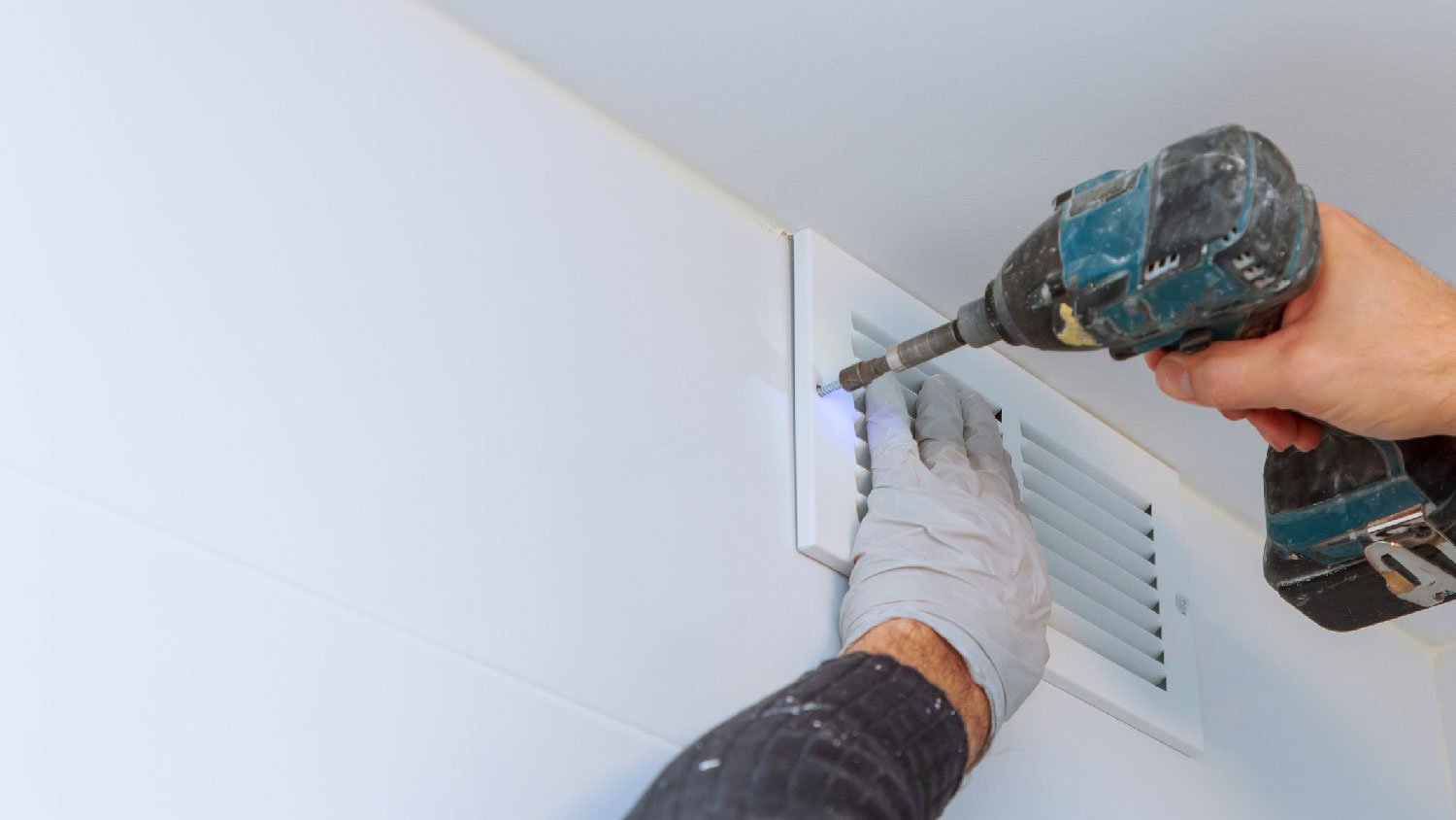 A man removing a vent cover