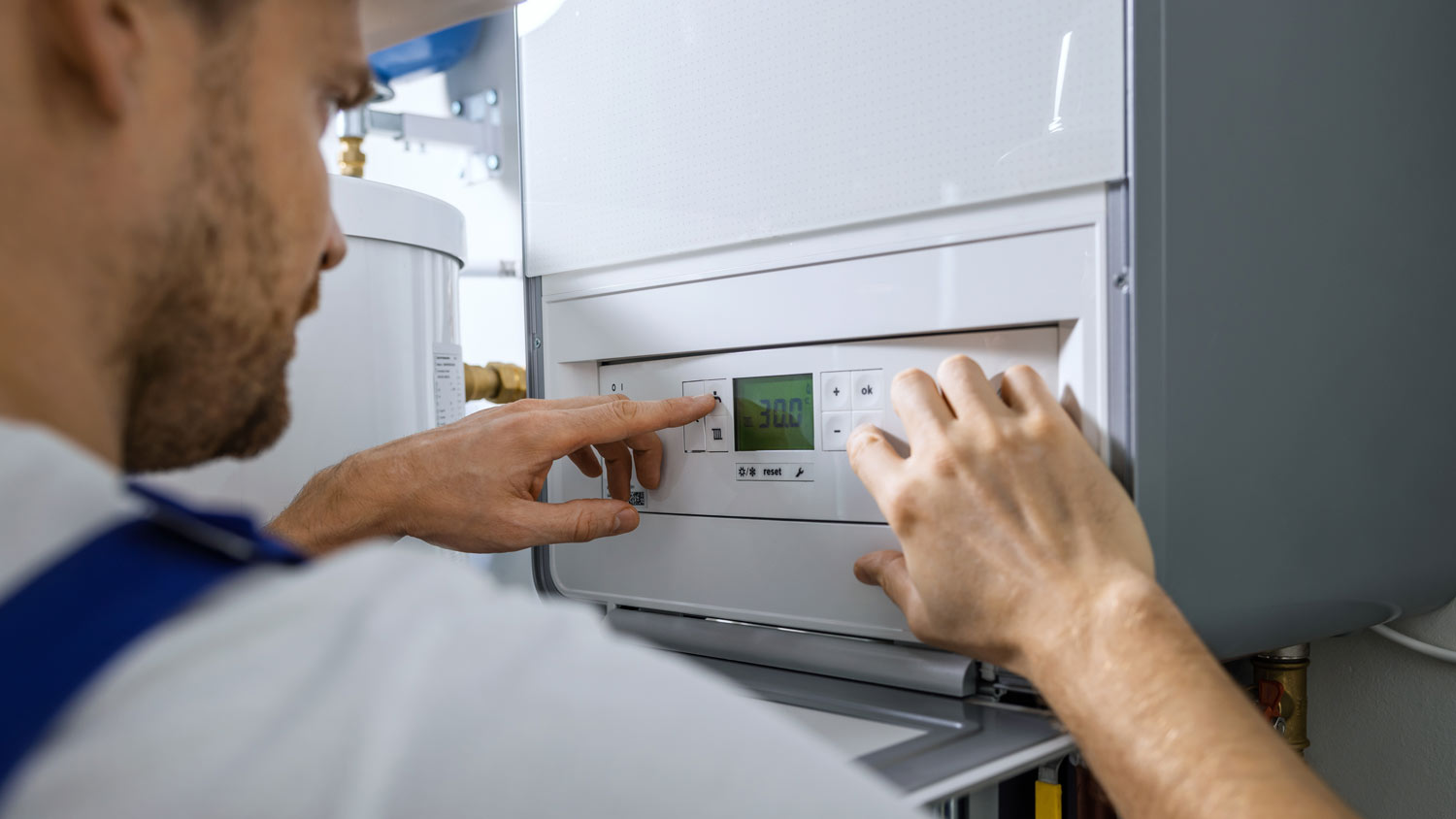 man doing maintenance check on boiler