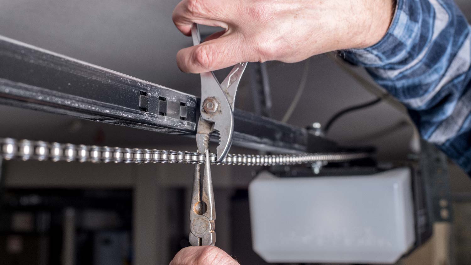 A man repairing a garage door chain