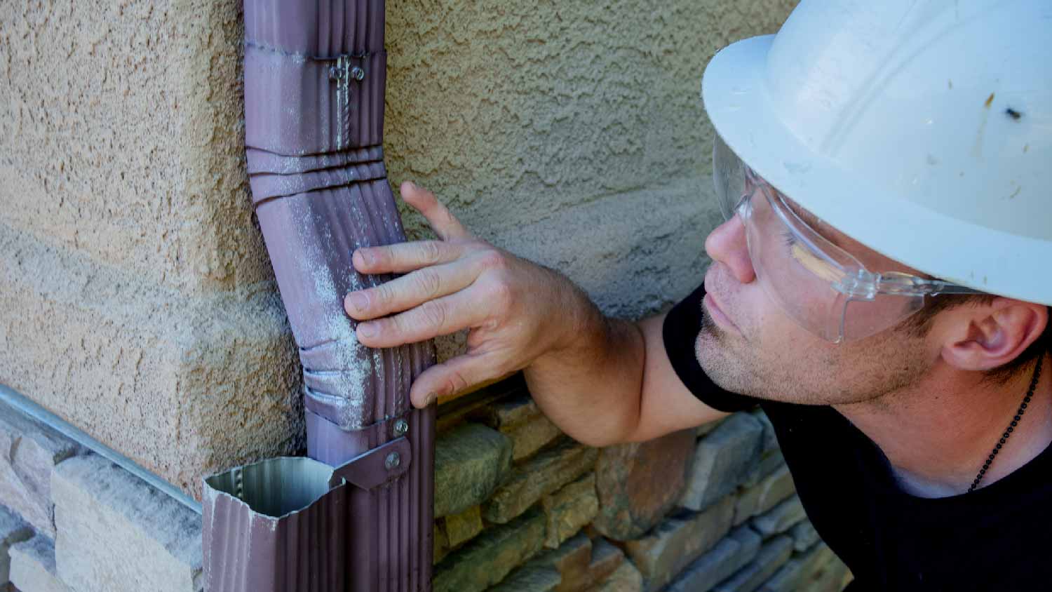 A man repairing an old downspout