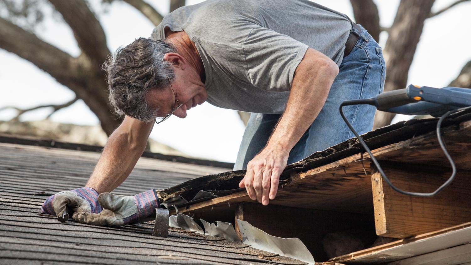 A man repairing rotten leaking roof