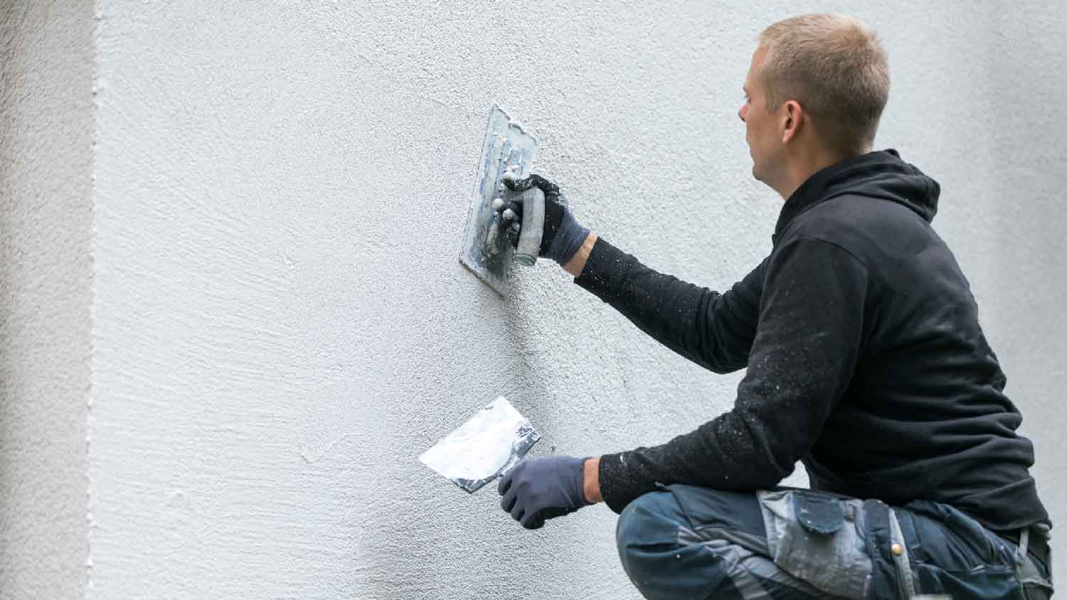 A man repairing a stucco wall 