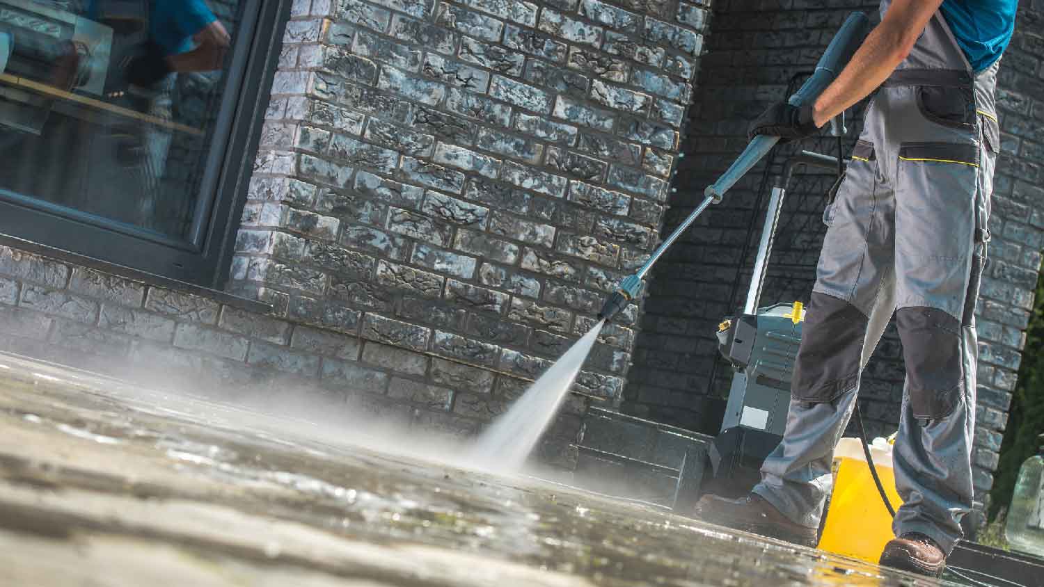 A man rinsing an asphalt driveway