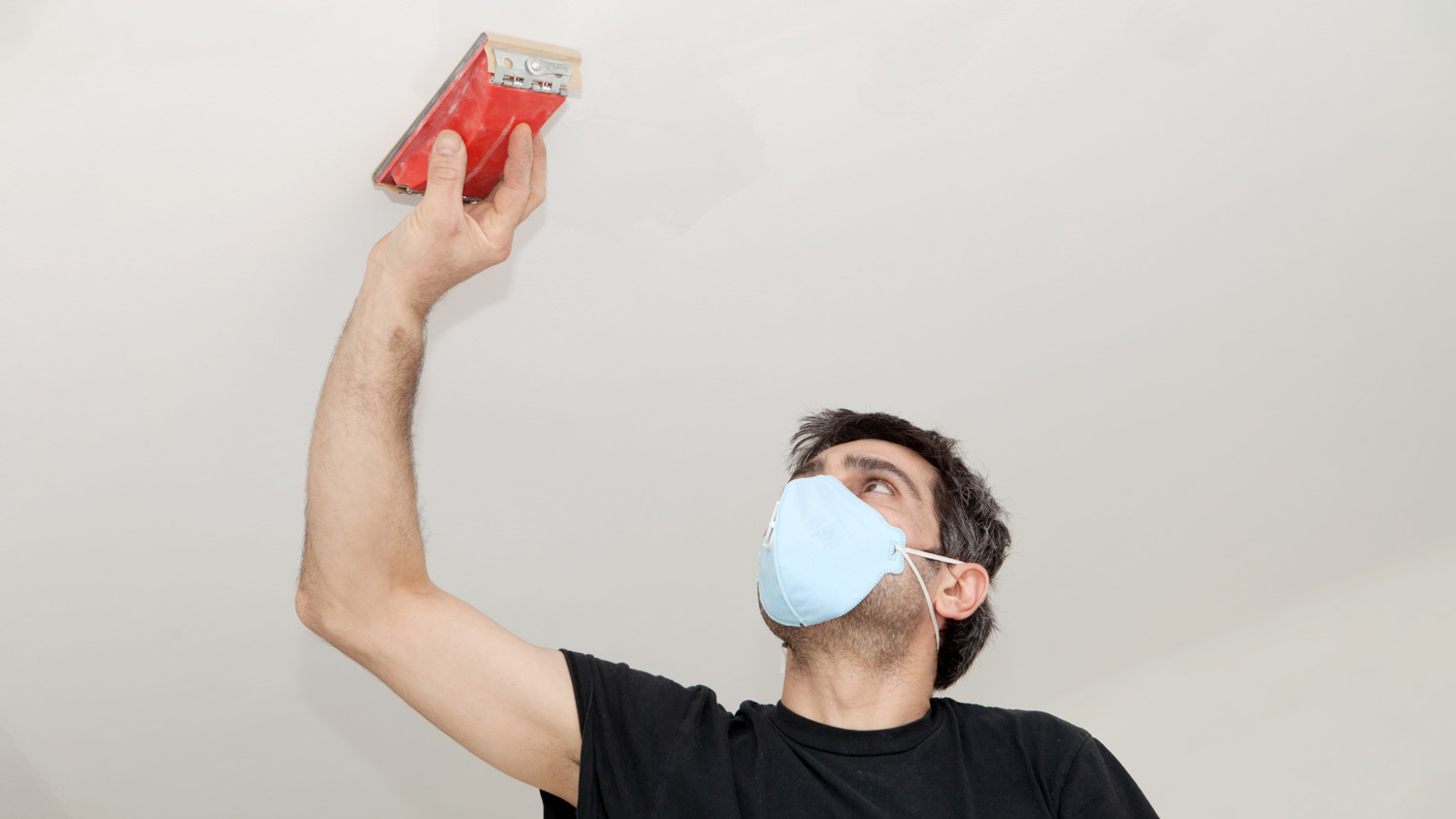 A man sanding the ceiling 