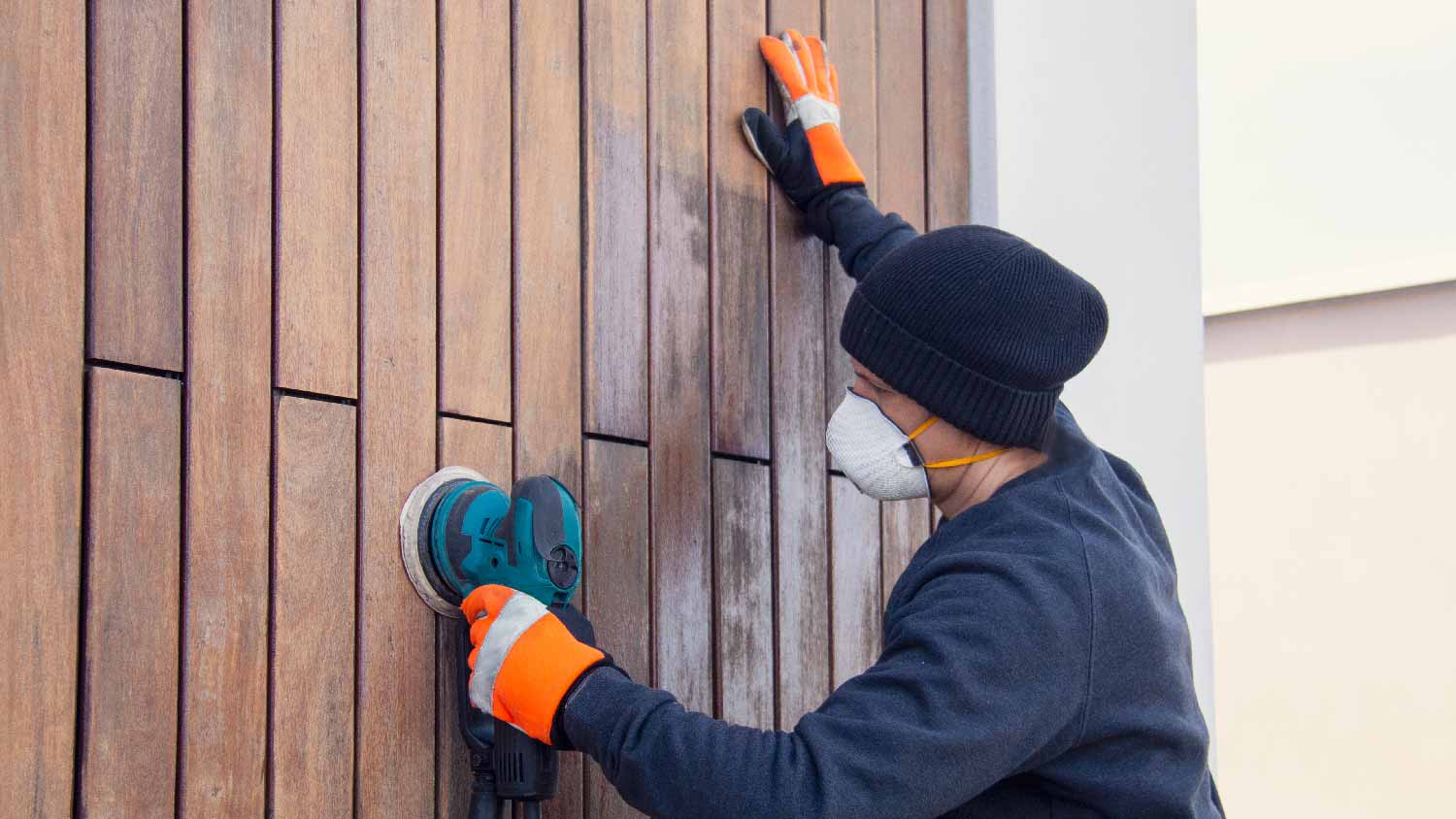  A man sanding teak cladding