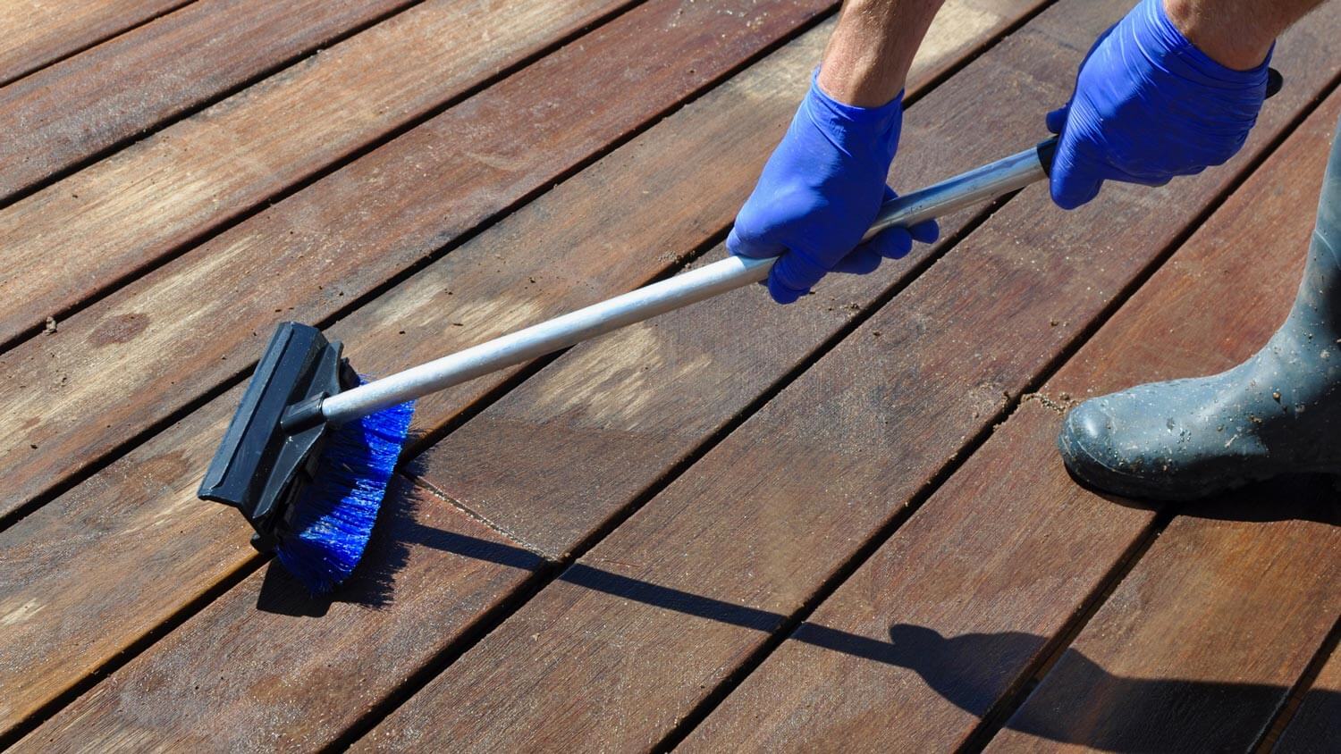 A man scrubbing a wooden deck with a brush