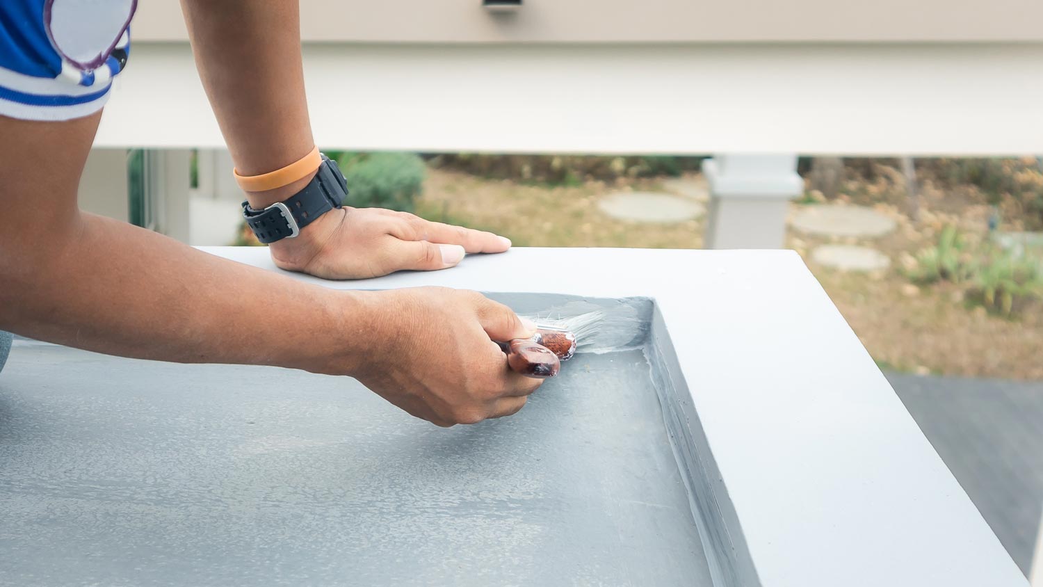 Close-up of a man sealing the deck with a brush