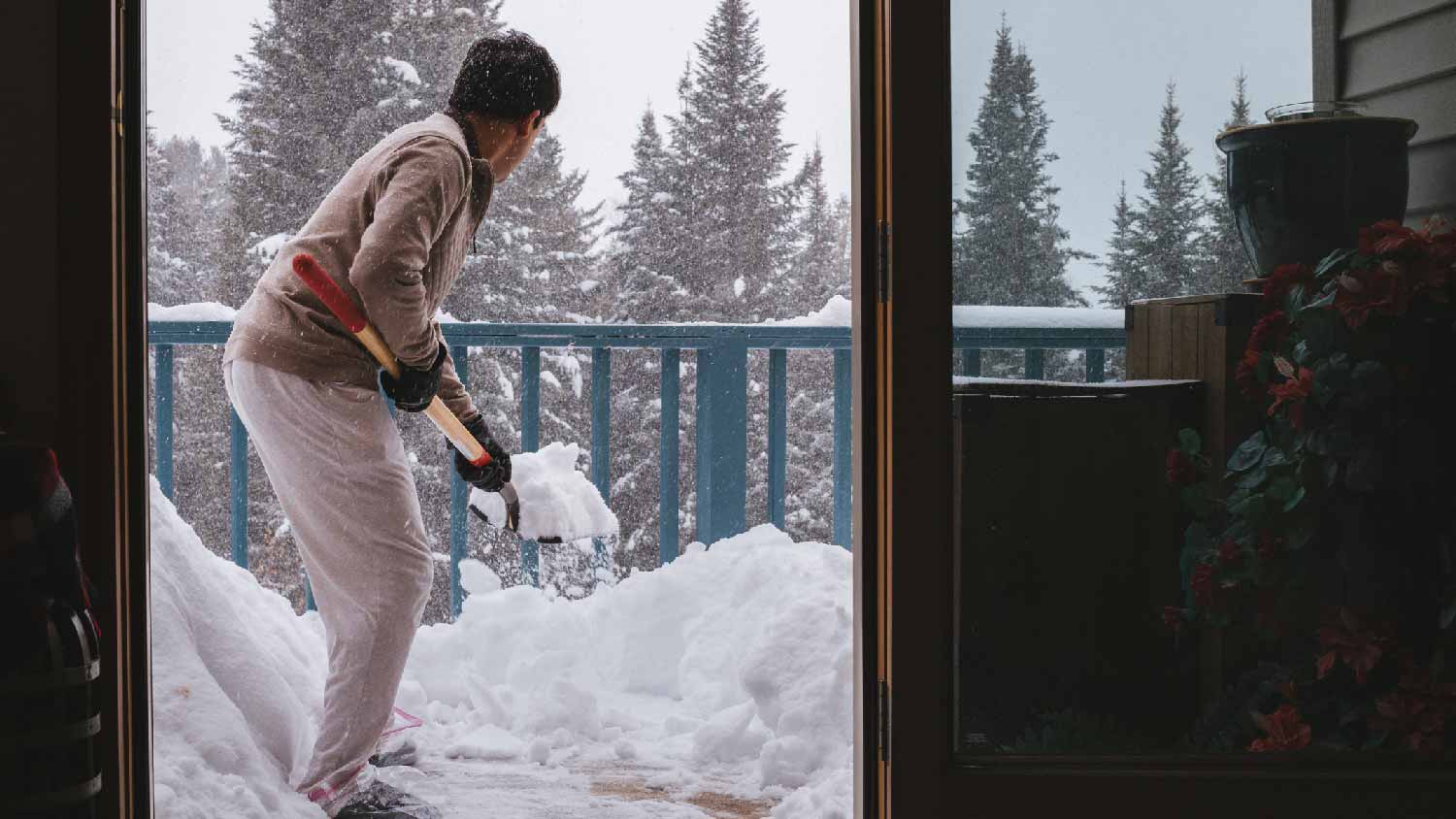A man shovelling snow from his deck