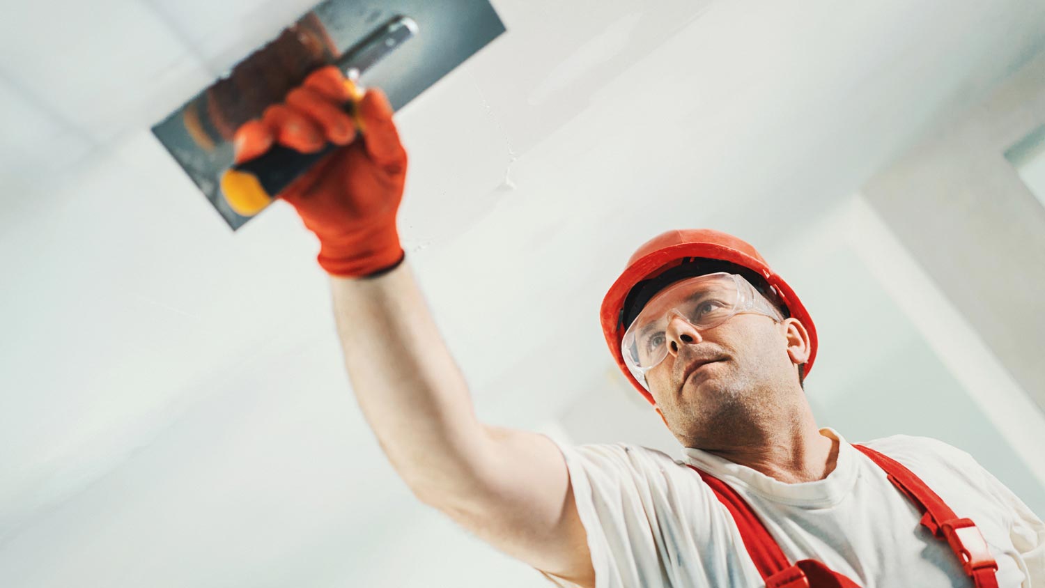 A man skim coating a wall