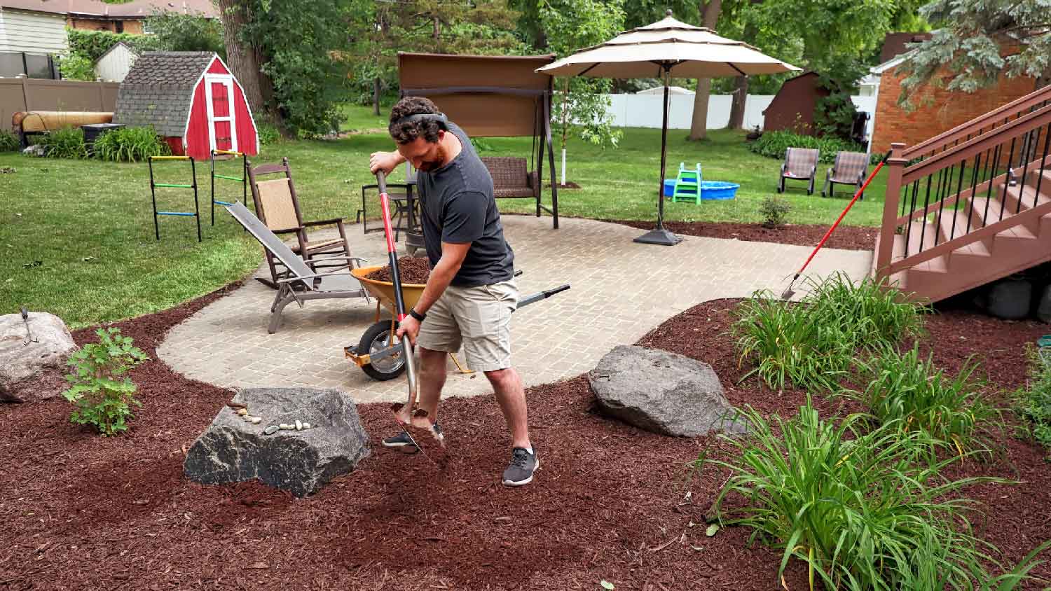 A man spreading mulch with a shovel