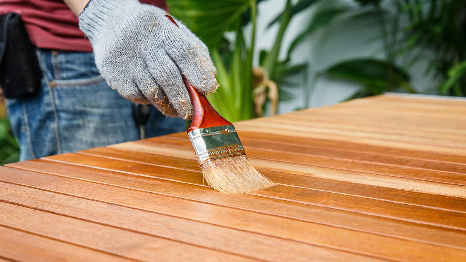 man staining wood table outside