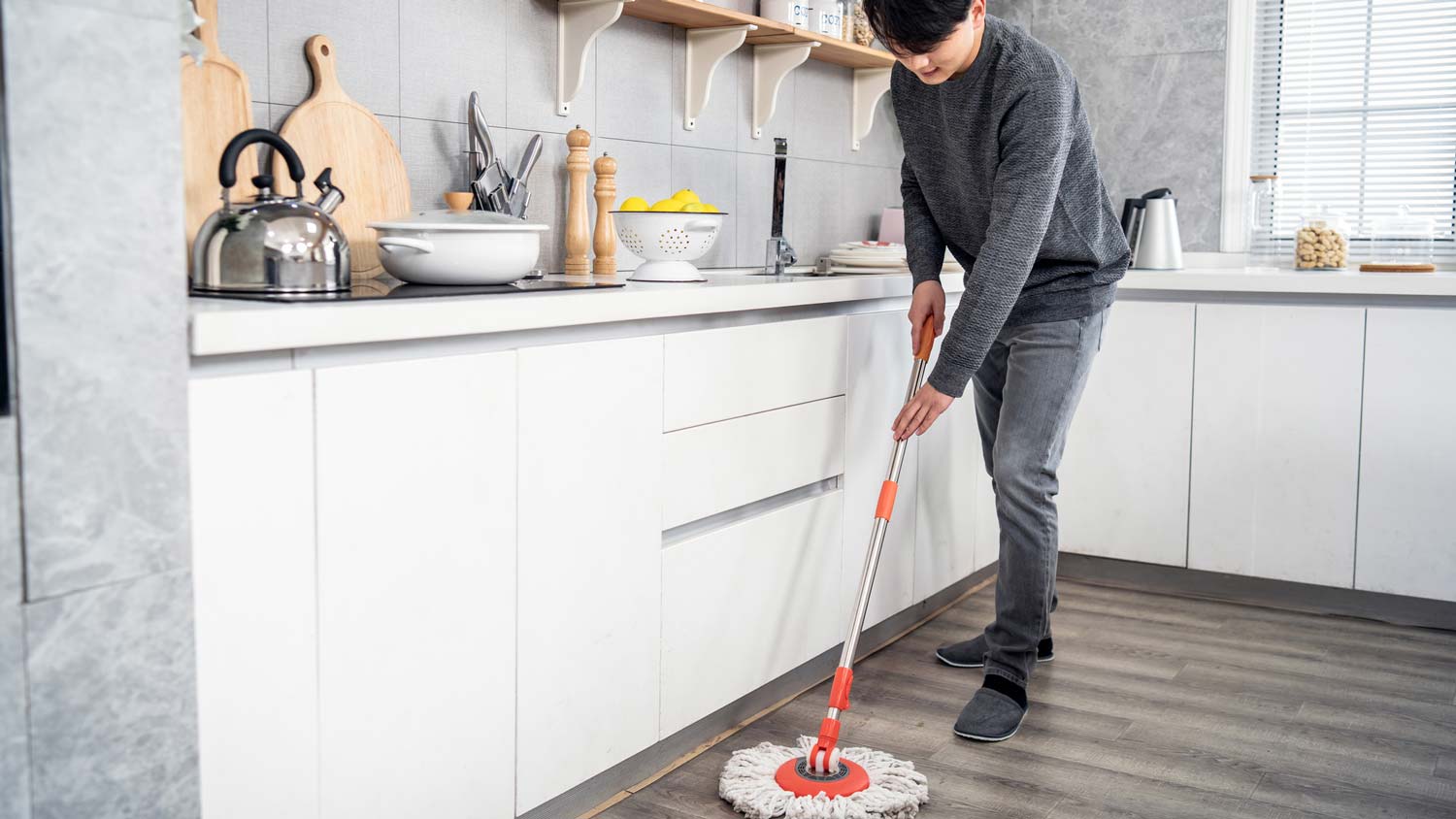 A man sweeping the floor in the kitchen 