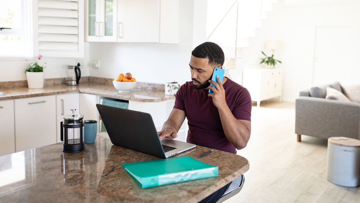 Man in the kitchen talking on the phone and taking notes